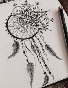 a drawing of a dream catcher with feathers on it's side and an ink pen in the foreground