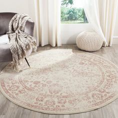 a round rug with an ornate design on the floor in front of a chair and window