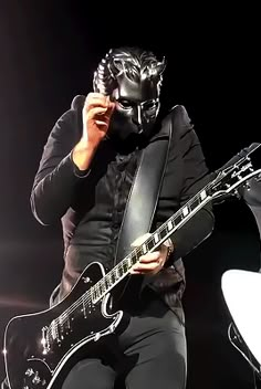 a man wearing a mask and holding a guitar