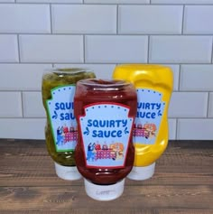 three jars of sauce sitting on top of a wooden table