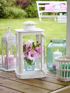 there is a vase with flowers in it sitting on the table next to two lanterns