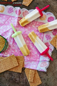 crackers and ice cream popsicles are sitting on a pink doily