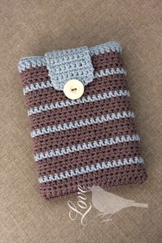 a crocheted cell phone case with a button on the front and side, sitting on a brown surface