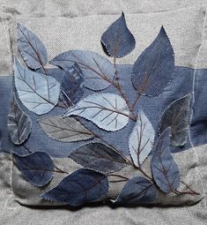 a close up of a blue pillow with leaves on it's back and sides