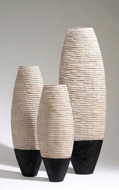 three black and white vases sitting next to each other on a white table top