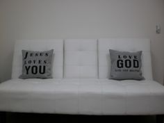 a white couch with two pillows that say jesus loves you and love your god on it