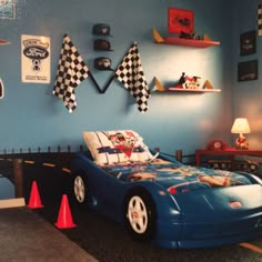 a child's bedroom with blue walls and race cars on the wall