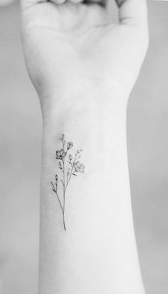 a small flower tattoo on the wrist is shown in this black - and - white photo