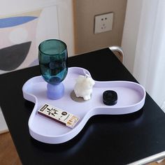 a tray with a glass and some items on it sitting on top of a table