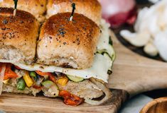 two sandwiches with toothpicks sticking out of them sitting on a wooden cutting board