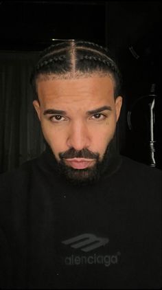 a man with long hair and a beard wearing a black shirt is looking at the camera