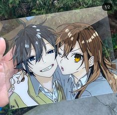 a person holding up a card with two anime characters on it