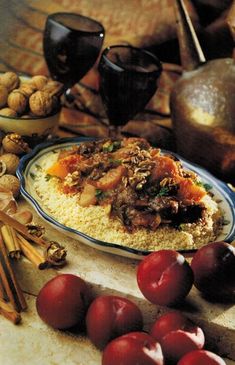 a plate of food with cherries and nuts on the table next to wine glasses