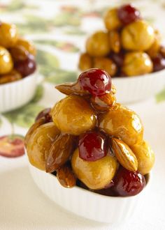 three small bowls filled with cherries on top of a white tablecloth covered table