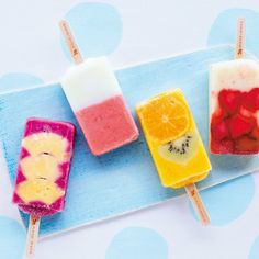 four popsicles with fruit on them sitting on a blue plate