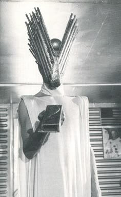 a man wearing a costume with spikes on his head and holding a book in one hand