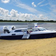 a white and blue boat sitting on top of a sandy beach