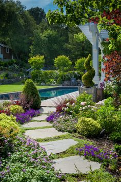 an outdoor garden with stone walkways and flowers in the foreground, surrounded by greenery