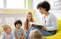 a woman sitting on top of a yellow bean bag chair next to two small children