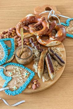 a wooden plate topped with cookies and pretzels on top of a table next to other items