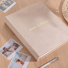 the wedding album is next to some photos and a pen on a wooden table with other personalized items