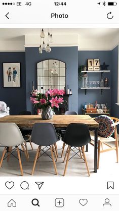 a dining room with blue walls and wooden table surrounded by chairs, vases and pictures on the wall