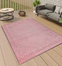 a pink area rug sitting on top of a hard wood floor next to a couch