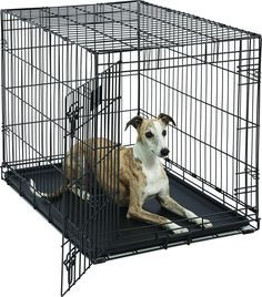 a dog sitting in a metal cage on top of a black cushioned mat that is attached to the floor