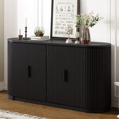 a black cabinet with two vases on top and a mirror above it in a living room