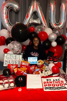 a woman sitting in front of a table with balloons and other items on top of it