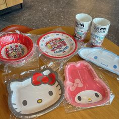 hello kitty plates and cups are sitting on a table with plastic wrap around the plates