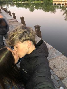 a man and woman kissing by the water