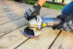 a person using a sander on a wooden deck