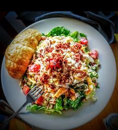 a white plate topped with salad next to a muffin