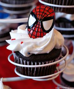 a spiderman cupcake with white frosting and sprinkles on top