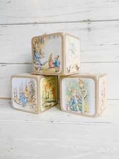 three wooden blocks with peter rabbit images on them sitting on a white wood floor next to each other