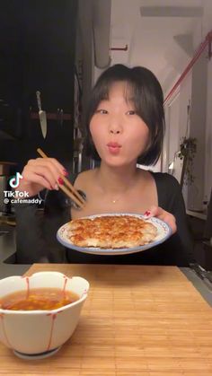 a woman holding a plate with food on it and chopsticks in front of her face