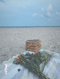 some flowers and a basket on the beach