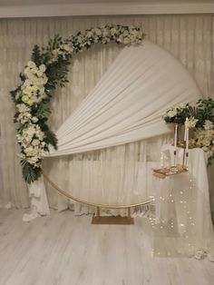 a white wedding arch decorated with flowers and greenery