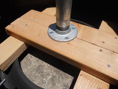 a close up of a wooden bench with a metal pole on it's end