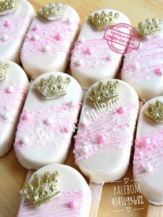 several decorated cookies with pink and gold frosting on wooden table next to each other