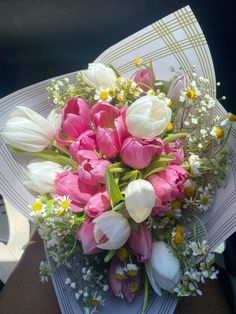 a bouquet of pink and white tulips on top of a piece of paper