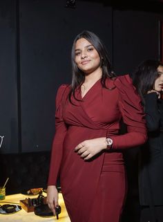 a woman in a red dress standing next to a table