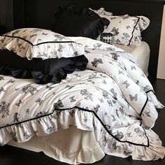 black and white bedding with ruffles on the bottom, along with pillows