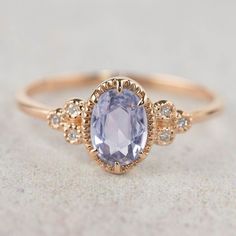 an oval blue topaz ring with three small diamonds on the band and a center stone surrounded by smaller stones