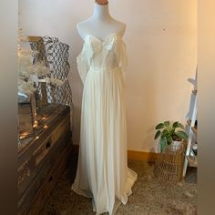 a white dress is on display in front of a wooden dresser and basket with flowers