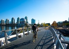 a person riding a bike on a bridge over water with city buildings in the background