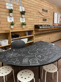 a chalkboard table with four stools in front of it and several bookshelves