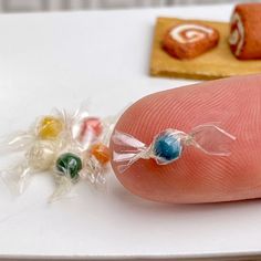 a finger with candy on it next to some candies