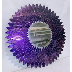 a purple flower shaped mirror hanging on the wall